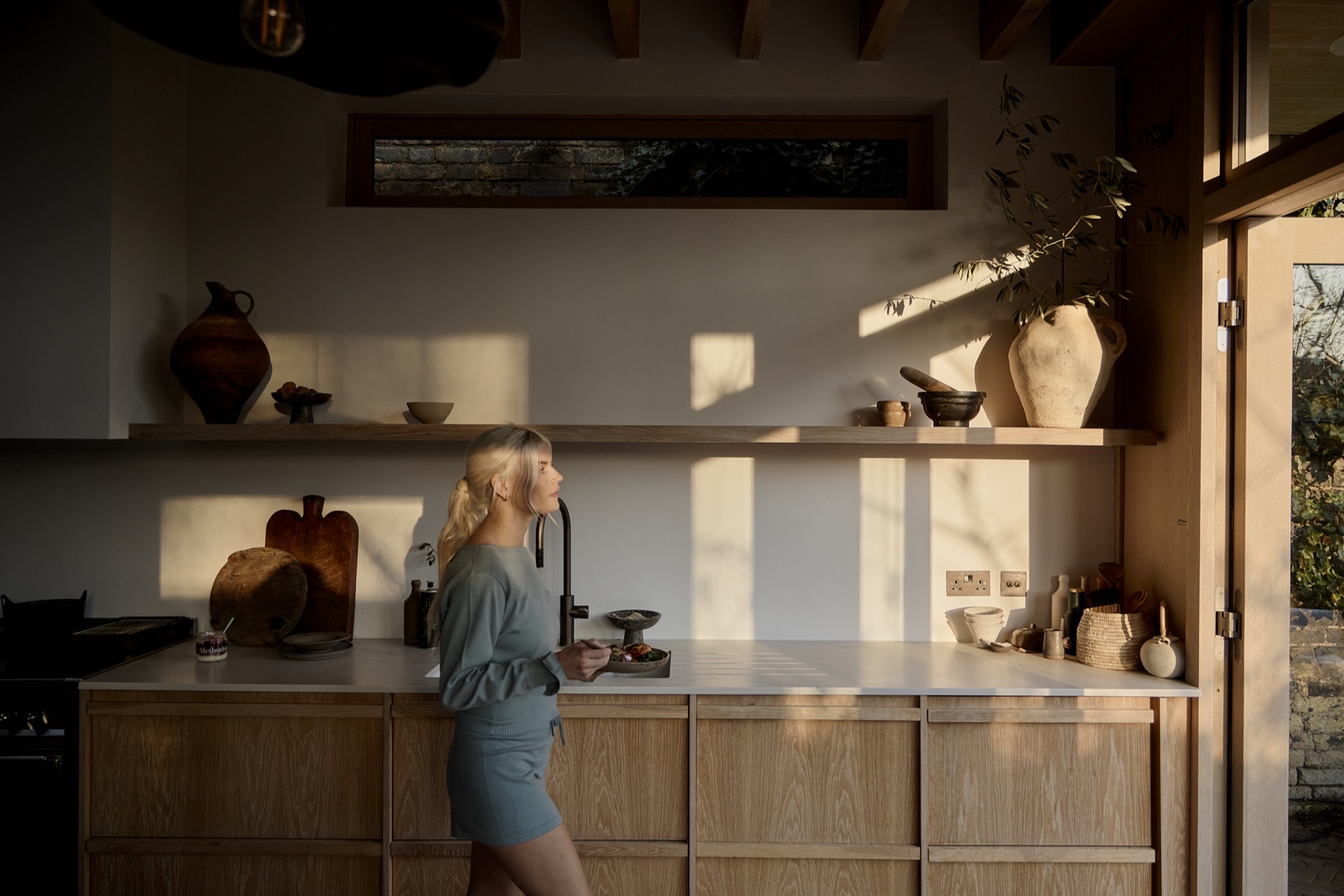 A woman standing in a sunlit kitchen